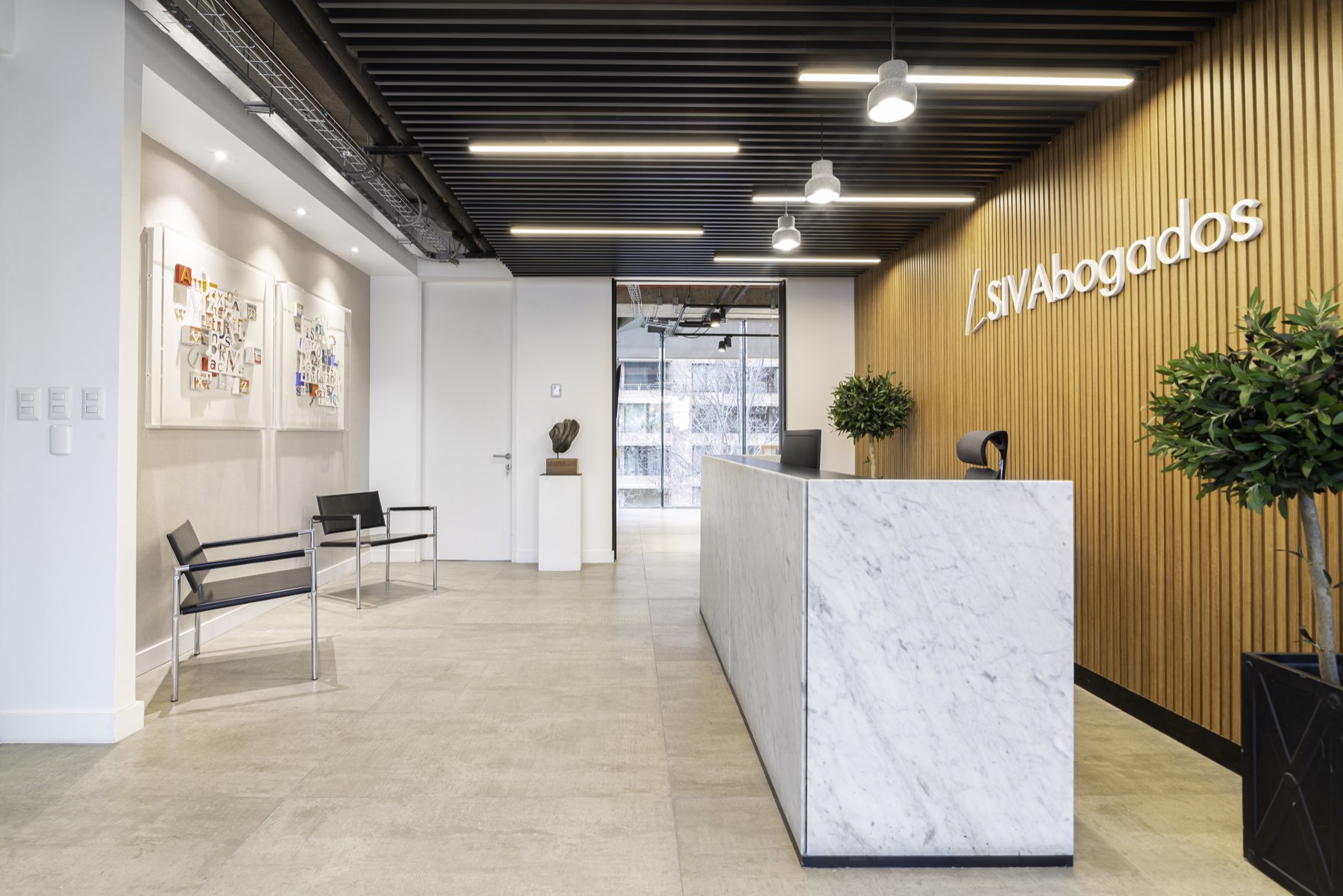 Recepción de SIV Abogados: mesón de mármol y muro de listones de madera con el logotipo del estudio