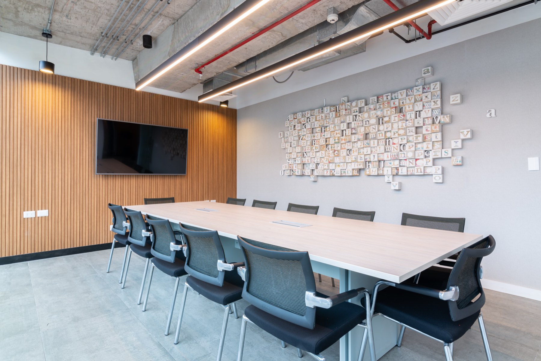 Sala de directorio con mesa larga y mural de fotografías del equipo